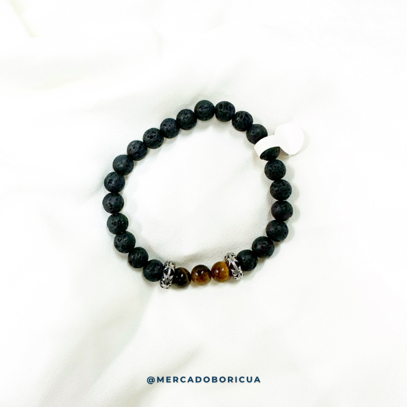 vista superior de una pulsera de cuarzo ojo de tigre y piedra volcanica negra con dos dijes de acero inoxidable labrados.